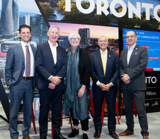5 business professionals stand in a row posing in front of toronto backdrop