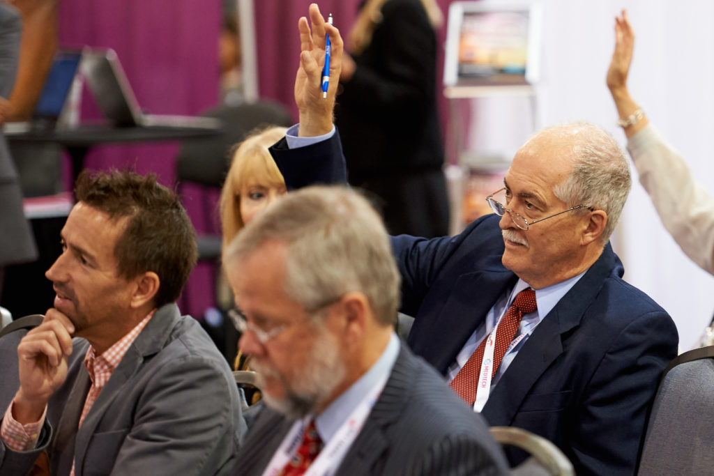business men and women in press and media raise hands