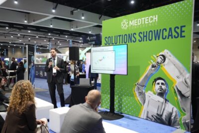 man in suit presenting in front of a screen at the medtech conference