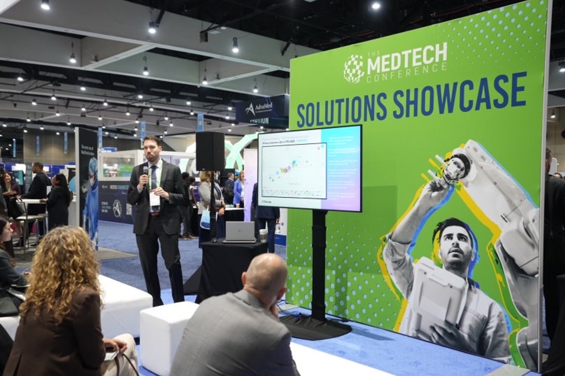 man in suit presenting in front of a screen at the medtech conference